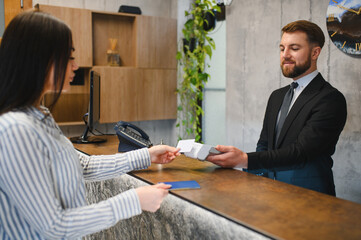 Guest checking in at hotel reception paying with credit card