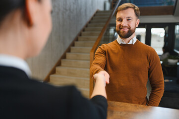 Business man greeting staff with handshake at reception desk