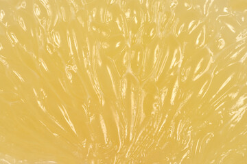 A detailed macro shot showing the glistening juice vesicles and internal structure of a fresh yellow grapefruit segment