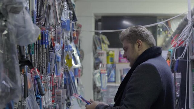 Professional Customer Inspecting Tools on Display Shelf in Hardware Store
