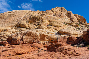 Fototapeta premium Vibrant red and white sandstone formations line the Calico Tanks Trail at Red Rock Canyon near Las Vegas. The moderate path winds through narrow canyons and rocky stairs, leading to a hidden natural w