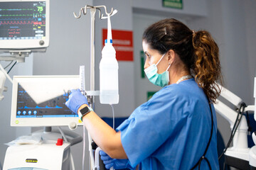 Nurse adjusting emergency medical equipment in icu