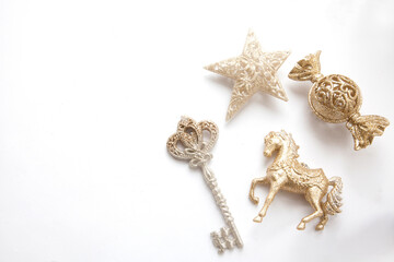 Gold Christmas ornaments&mdash;star, candy, key and horse&mdash;arranged on a clean white background with copy space. Elegant festive flat lay for holiday design and advertising.
