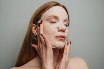 Obraz premium Redhead woman demonstrating facial skincare routine closeup