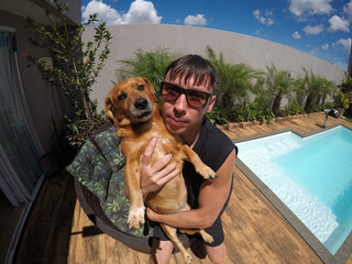 homem com cachorro em piscina no ver&atilde;o 