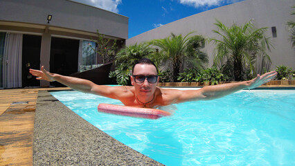 homem de f&eacute;rias relaxa na piscina no ver&atilde;o 