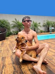 homem com cachorro em area de lazer com piscina 