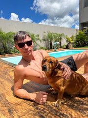 homem com cachorro em area de lazer com piscina 