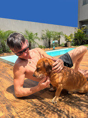 homem com cachorro em area de lazer com piscina 