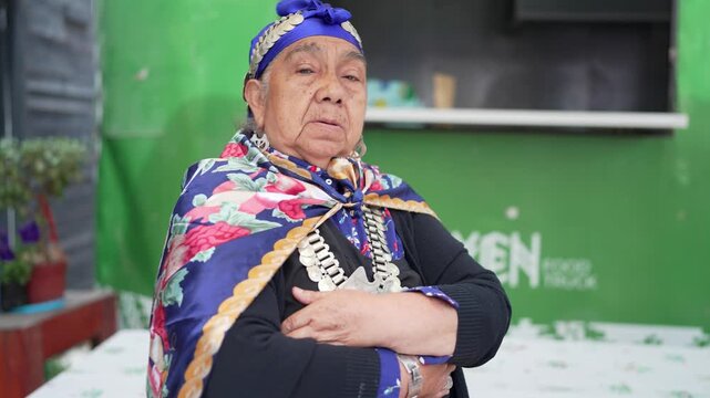 Elderly indigenous mapuche woman with a serious expression wearing traditional clothes and jewelry