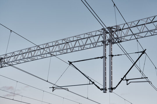 Overhead railway catenary and power lines against clear sky, electrified rail transport infrastructure background with copy space.