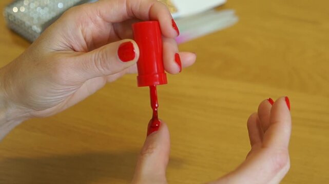Macro shot of a professional brush applying red lacquer to a fingernail.