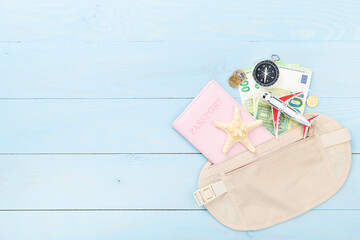 Traveler organizer bag with passport and accessories on wooden background, top view