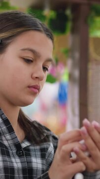 latina teen concentrating on nails, flannel shirt, hands prepping polish, colorful market bokeh, soft natural light, hairclip detail, calm expression, closeup portrait, tactile grooming moment