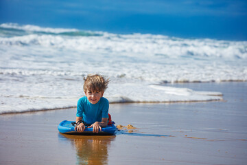 Obraz premium Young boy have fun bodyboarding at sunny beach day on vacations