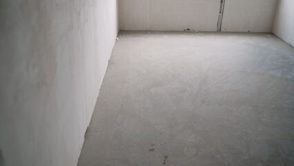 Empty room with concrete floor and white walls during renovation