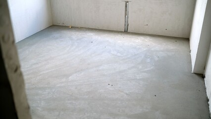 Concrete floor in empty apartment under construction