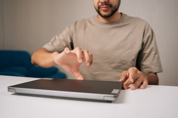 Cropped shot of bearded businessman opening laptop preparing to work in home office, feeling satisfied and productive after successful day of remote work, close-up. Concept of remote workplace.