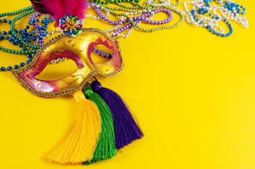 Top view of a beautiful composition of colorful masks, confetti, Mardi Gras decorations. Yellow Mardi Gras banner.