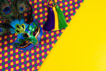 Top view of a beautiful composition of colorful masks, confetti, Mardi Gras decorations. Yellow Mardi Gras banner.
