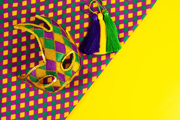Top view of a beautiful composition of colorful masks, confetti, Mardi Gras decorations. Yellow Mardi Gras banner.