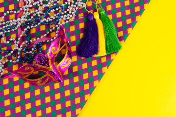 Top view of a beautiful composition of colorful masks, confetti, Mardi Gras decorations. Yellow Mardi Gras banner.