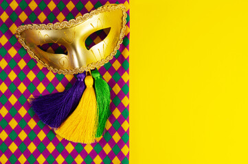 Top view of a beautiful composition of colorful masks, confetti, Mardi Gras decorations. Yellow Mardi Gras banner.