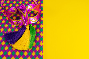 Top view of a beautiful composition of colorful masks, confetti, Mardi Gras decorations. Yellow Mardi Gras banner.