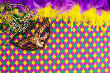 Top view of a beautiful composition of colorful masks, confetti, Mardi Gras decorations. Yellow Mardi Gras banner.