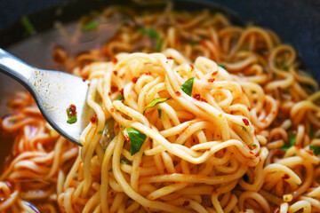 Instant noodles on fork in a bowl. Spicy noodle soup. Asian food style.