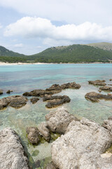 Rocky shoreline with clear turquoise water and hills.. Palma de Mallorca, Spain