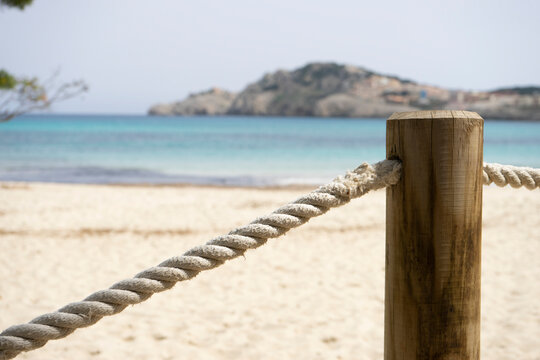 Rope fence near sandy beach and turquoise water.. Palma de Mallorca, Spain