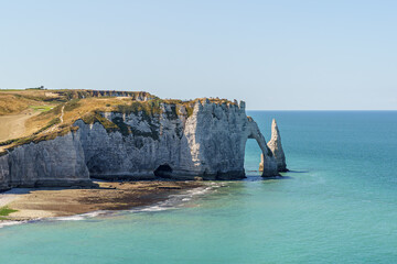 A beautiful blue ocean with a cliff in the background in Etretat France Normandy The cliff is a part of a larger rock formation The shape of the stone arch resembles an elephant's trunk