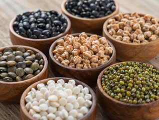Fototapeta premium Close-up of a rustic spread: black beans, chickpeas, green mung beans, and assorted lentils in wooden bowls on a weathered table