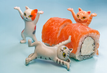 Team of joyful cat figurines playing with fresh salmon and cream cheese sushi. Humorous scene for a food ordering service and menu design. High resolution. Photo