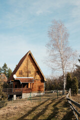 A frame wooden cabin standing on open meadow near forest in Tara National Park, Serbia. Minimal mountain housing under clear sky.