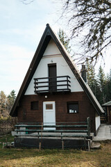Front view of alpine style wooden cabin surrounded by forest vegetation in Tara National Park, Serbia. Quiet mountain home in wilderness.