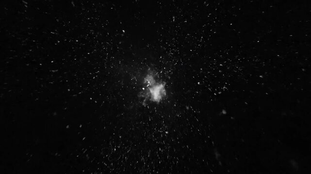 Black and white abstract shot of explosion with white particles and flashes in darkness environment