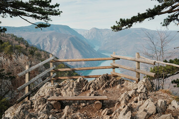 View from Banjska Stena viewpoint overlooking Drina River canyon and Perucac Lake in Tara National Park, Serbia. Rocky lookout with wooden fence above mountain landscape.