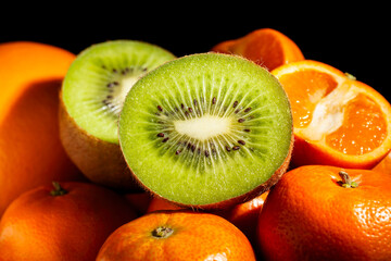 sliced kiwi tangerine heap on black background