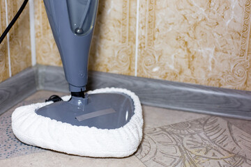 Steam cleaner with a white microfiber pad is positioned on a patterned floor, showcasing its cleaning capabilities and modern design in a domestic environment