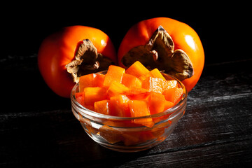 chopped persimmon on black wood background