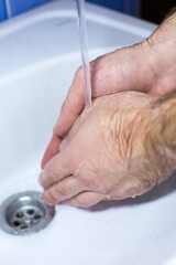 Fototapeta premium Close-up of hands washing under running water in a sink, showcasing hygiene practices and cleanliness, emphasizing the importance of handwashing in daily routines