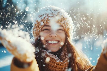 A woman wearing a hat and scarf is smiling broadly as she embraces the falling snowflakes. She appears happy and excited by the winter weather.