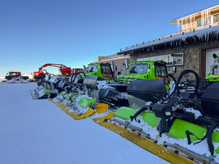 Powerful snow grooming vehicles lined up and ready at dawn on the pristine slopes of a ski resort,...