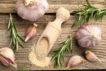 Granulated dried garlic, scoop, rosemary and fresh vegetables on wooden table, flat lay