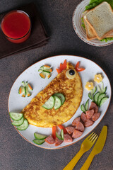 Breakfast food art of kids - funny chick egg omelet with sausage, vegetables, bread and tomato juice