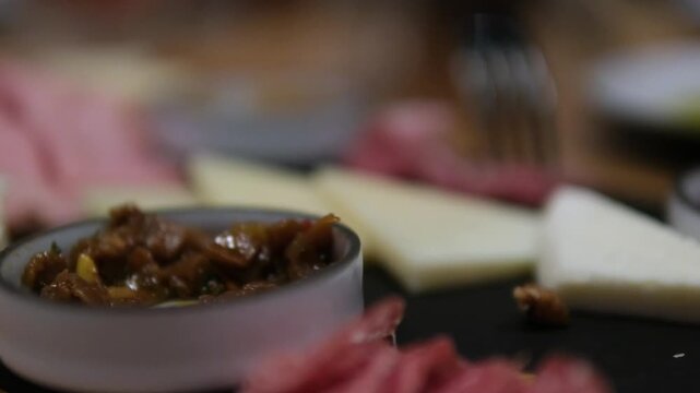 Taking meat with a fork from Charcuterie board with various cured meats and sausages close up. High quality 4k footage