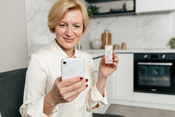 Senior woman managing her medication while using a smartphone at home