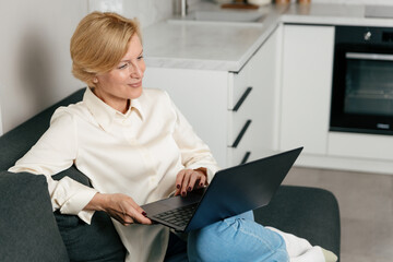 Woman using a laptop while sitting on a couch in a modern apartment
